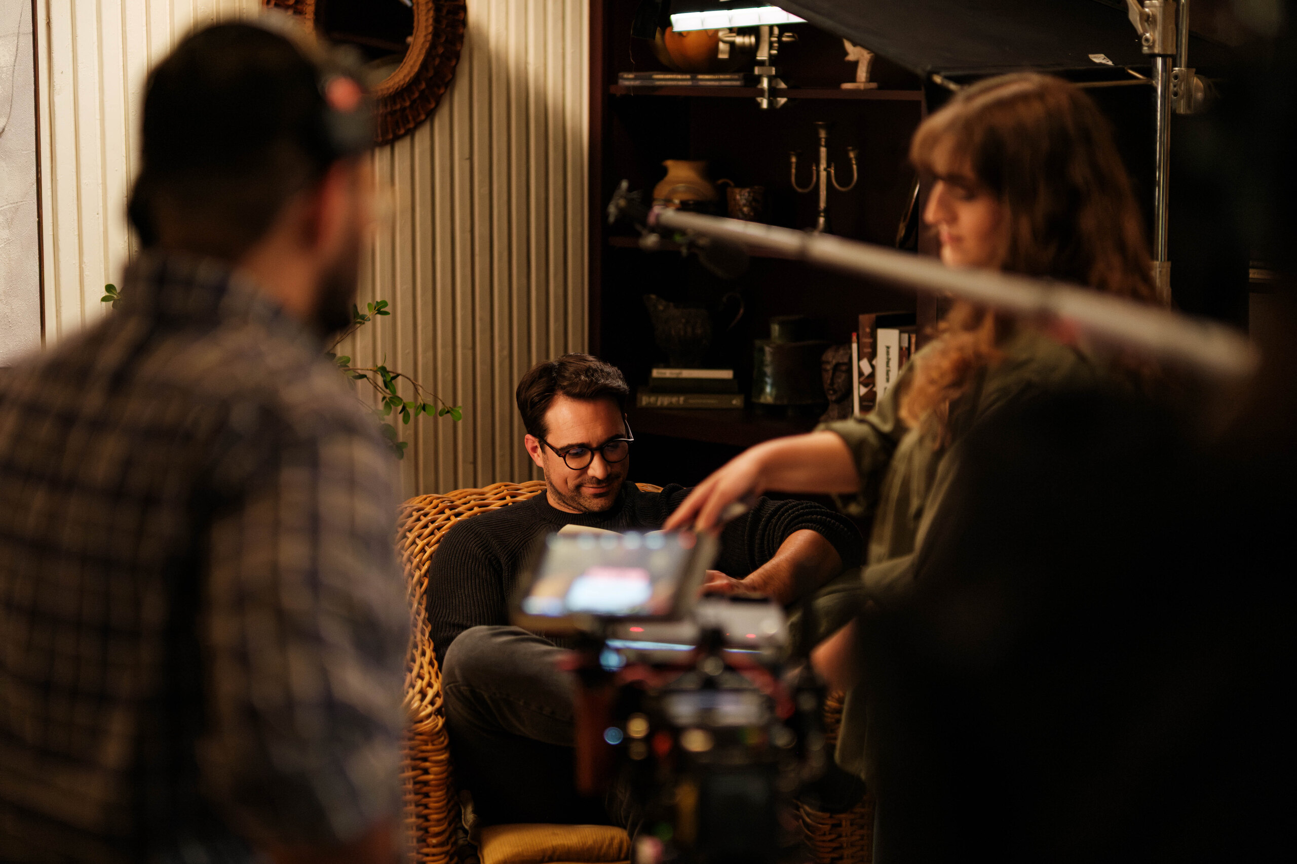 The crew gathers around the camera in the living room.